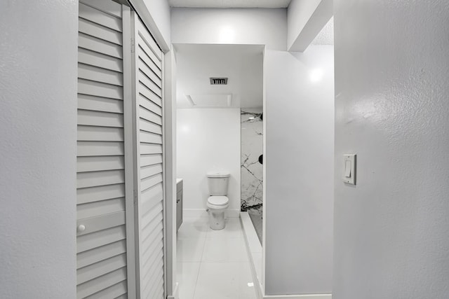 bathroom featuring a tile shower, tile patterned flooring, vanity, and toilet