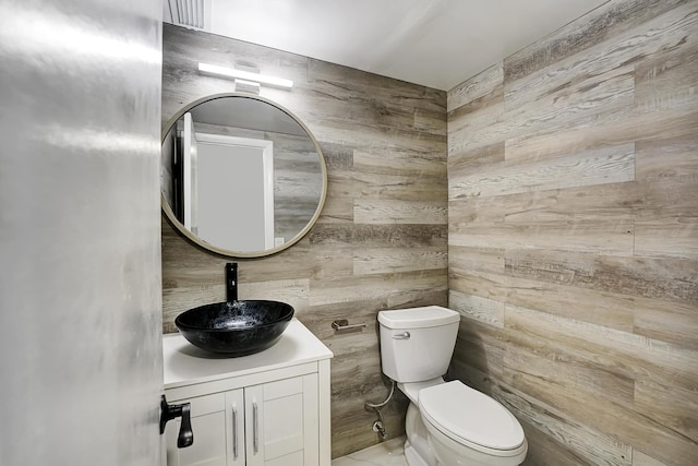 bathroom with vanity, wood walls, and toilet