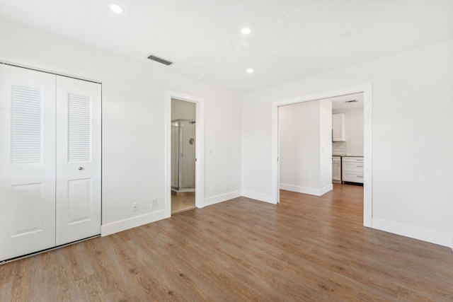 unfurnished bedroom with light hardwood / wood-style flooring, a closet, and ensuite bathroom