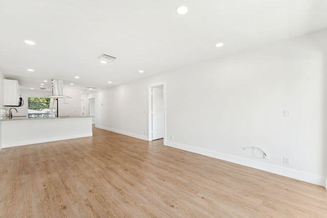 unfurnished living room with light wood-type flooring and sink