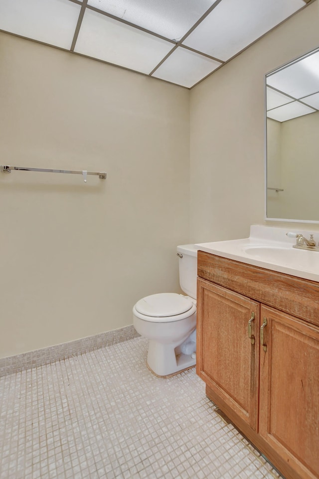 bathroom featuring tile patterned flooring, a paneled ceiling, vanity, and toilet