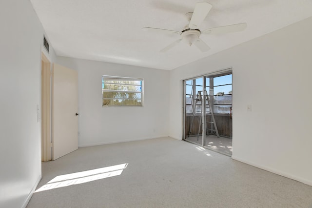 carpeted empty room featuring ceiling fan and plenty of natural light