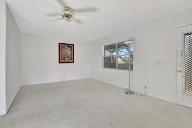 spare room with ceiling fan, a textured ceiling, and light carpet