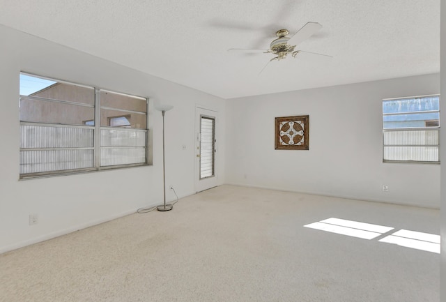 carpeted spare room featuring a textured ceiling and ceiling fan