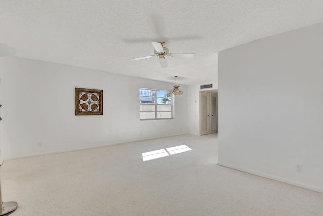 spare room featuring light carpet, ceiling fan, and a textured ceiling