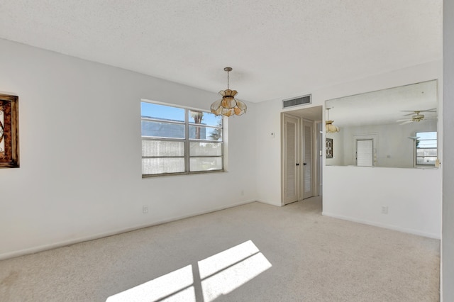 empty room featuring a textured ceiling, light colored carpet, and ceiling fan