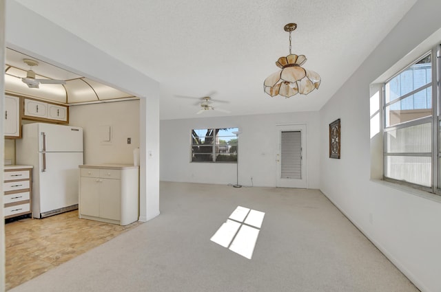 interior space featuring a textured ceiling, ceiling fan, light carpet, and white refrigerator