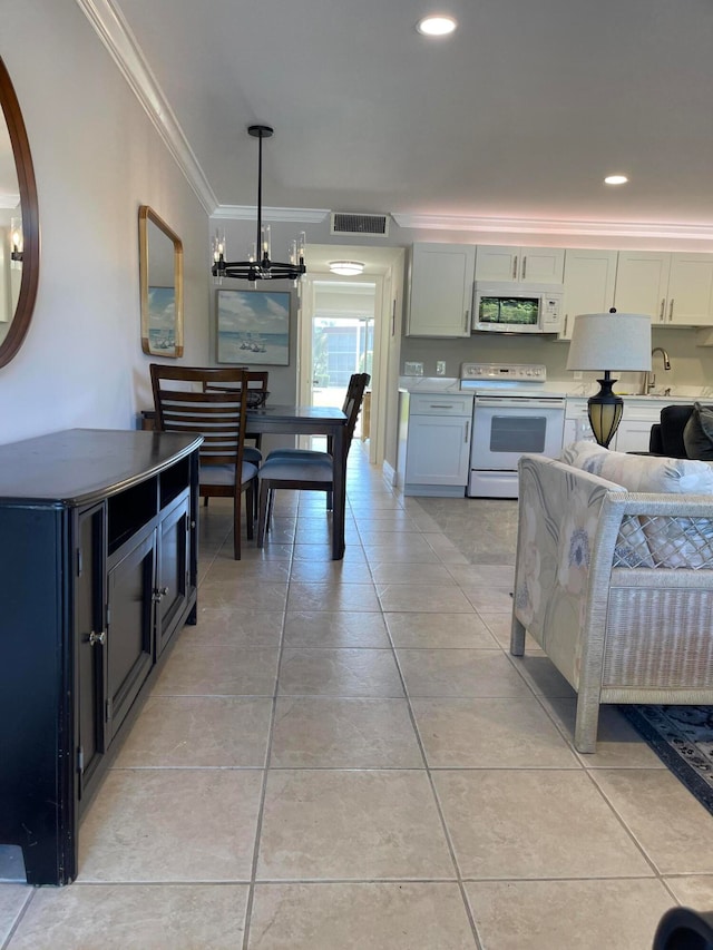 kitchen featuring ornamental molding, white appliances, decorative light fixtures, white cabinetry, and an inviting chandelier