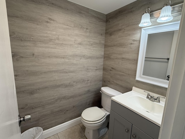 half bath featuring vanity, tile patterned flooring, wood walls, and toilet