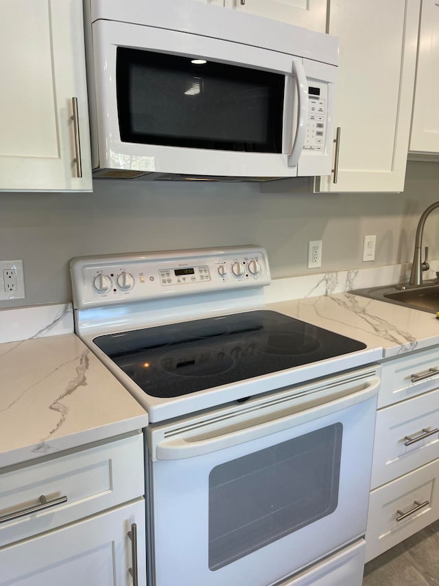 kitchen featuring white cabinets, sink, white appliances, wood-type flooring, and light stone countertops