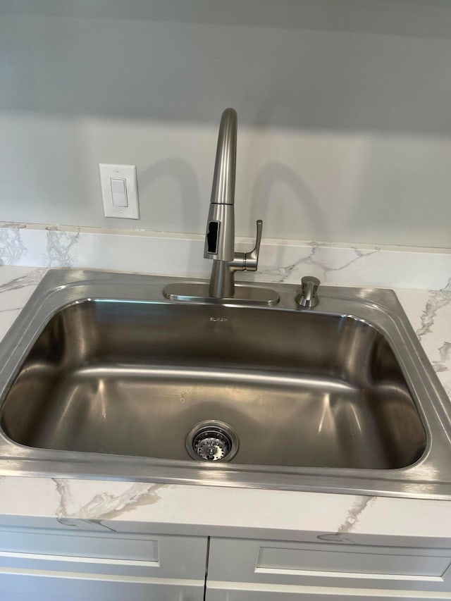 interior details featuring white cabinetry and sink