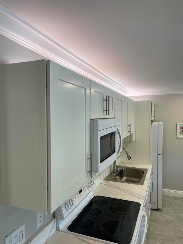 kitchen featuring light stone counters, sink, white appliances, crown molding, and light hardwood / wood-style floors