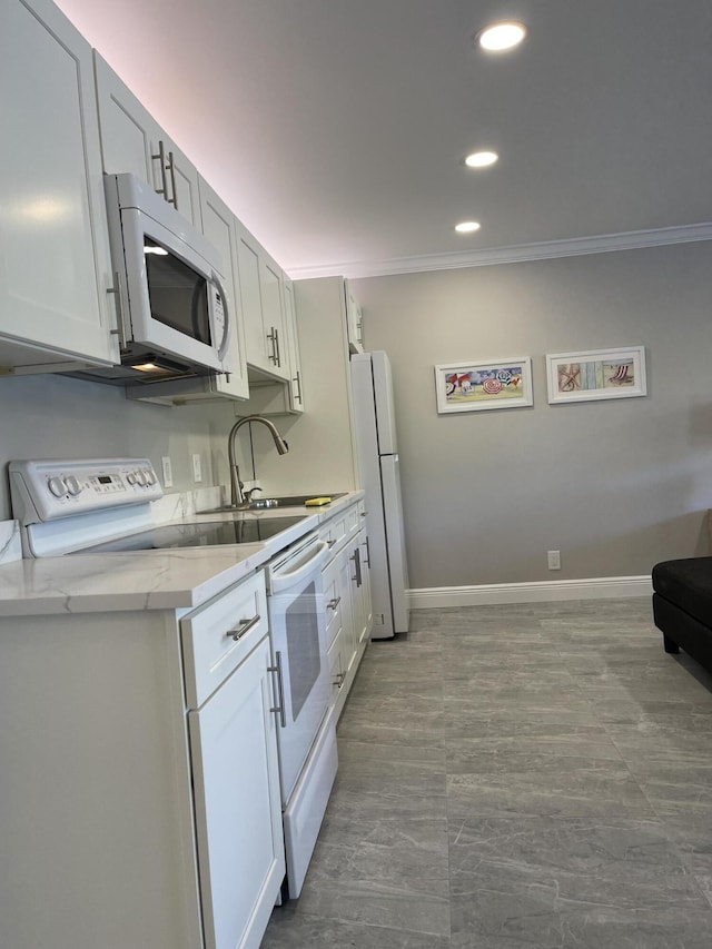 kitchen with ornamental molding, white appliances, recessed lighting, light countertops, and a sink