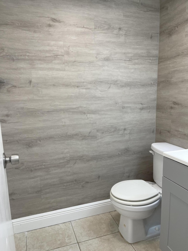 half bathroom with vanity, tile patterned flooring, and toilet