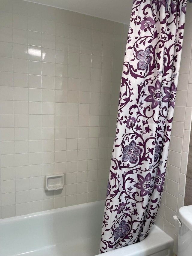 bathroom featuring shower / tub combo and toilet