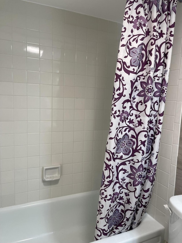 bathroom with toilet and shower / bathtub combination with curtain