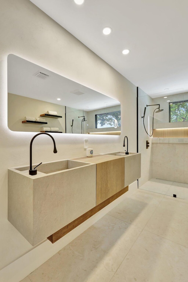 bathroom with a tile shower, vanity, and a healthy amount of sunlight