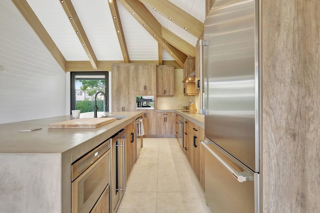 kitchen with vaulted ceiling with beams, beverage cooler, high quality fridge, and sink