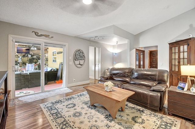 living room featuring hardwood / wood-style flooring, ceiling fan, lofted ceiling, and a textured ceiling