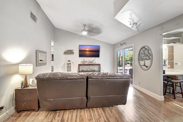 living room featuring a textured ceiling, ceiling fan, lofted ceiling, and hardwood / wood-style flooring