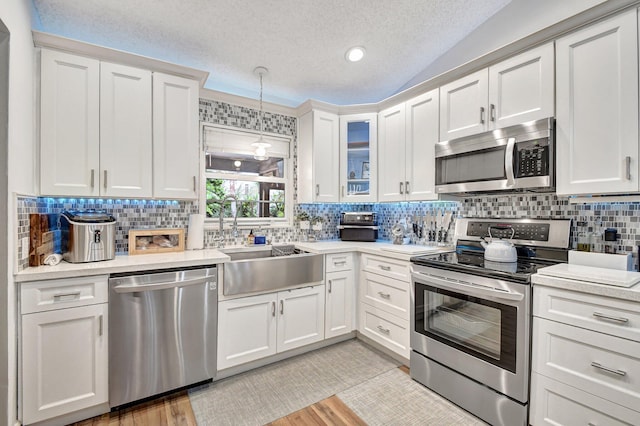 kitchen with white cabinetry, stainless steel appliances, lofted ceiling, a textured ceiling, and ornamental molding