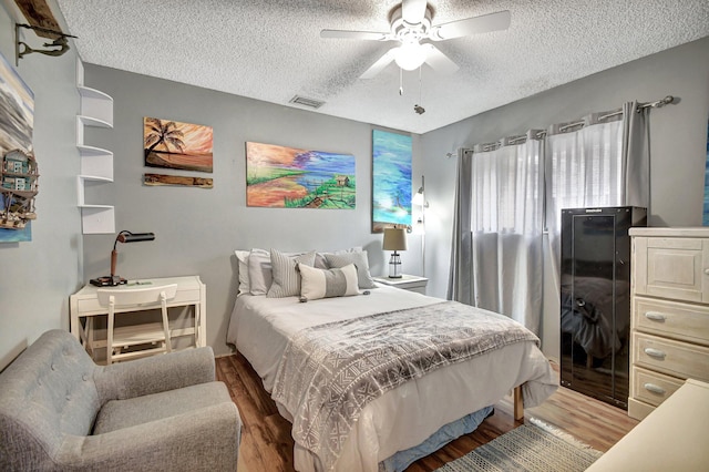 bedroom with ceiling fan, hardwood / wood-style floors, and a textured ceiling