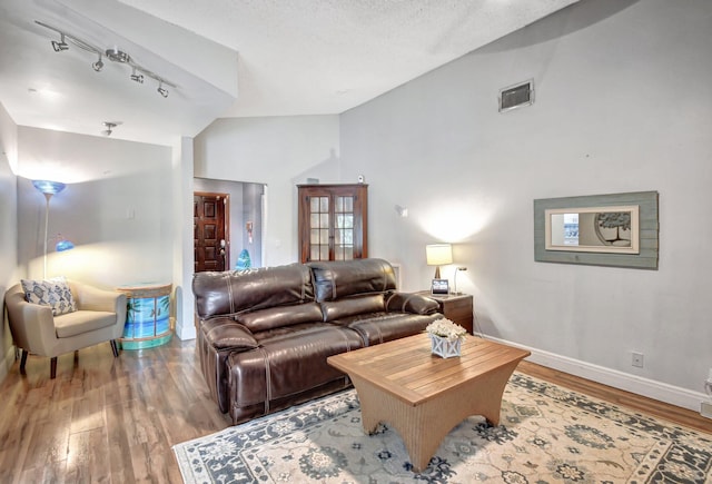 living room with hardwood / wood-style flooring, a textured ceiling, and high vaulted ceiling