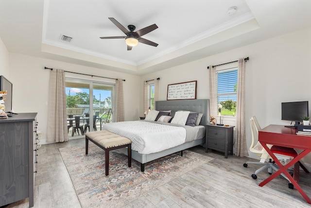 bedroom with light wood-type flooring, a tray ceiling, ceiling fan, and access to exterior