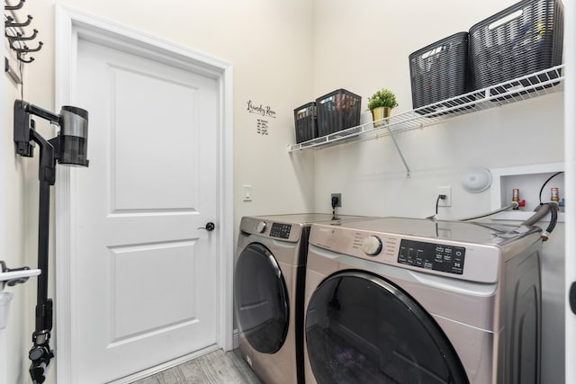 laundry room with washing machine and clothes dryer and light hardwood / wood-style flooring