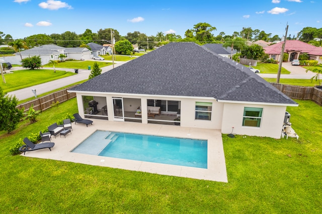 back of property with a fenced in pool, a sunroom, a yard, and a patio