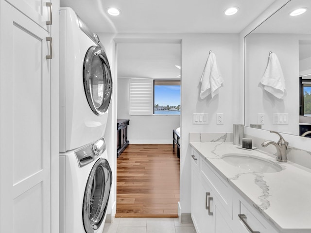 washroom with a wealth of natural light, sink, light tile patterned flooring, and stacked washer and clothes dryer