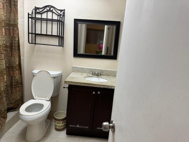 bathroom featuring tile patterned floors, vanity, walk in shower, and toilet