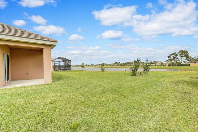 view of yard with glass enclosure and a water view