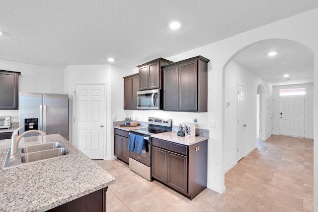 kitchen with appliances with stainless steel finishes, dark brown cabinetry, and sink