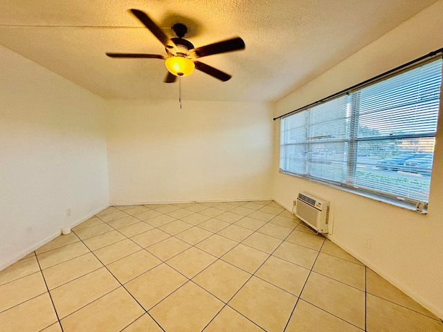 spare room with a wall mounted air conditioner, a textured ceiling, ceiling fan, and light tile patterned flooring