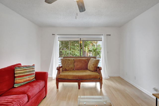 living area featuring light hardwood / wood-style flooring, a textured ceiling, and ceiling fan