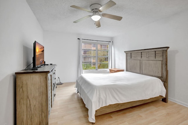 bedroom with a textured ceiling, light wood-type flooring, and ceiling fan