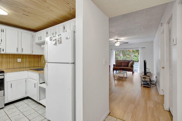 kitchen featuring light hardwood / wood-style floors, white cabinets, white fridge, and ceiling fan