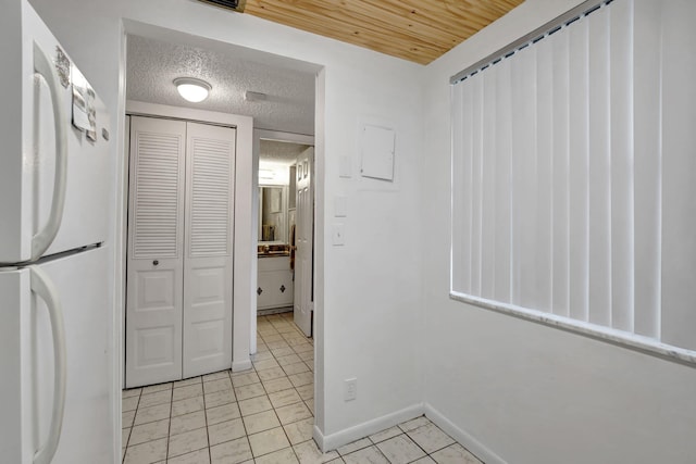 kitchen with white fridge, a textured ceiling, and light tile patterned floors