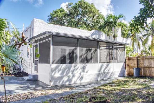 view of side of property featuring entry steps, fence, and a sunroom