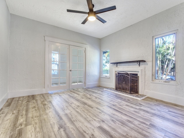 unfurnished living room with ceiling fan, light wood-type flooring, a textured ceiling, and french doors