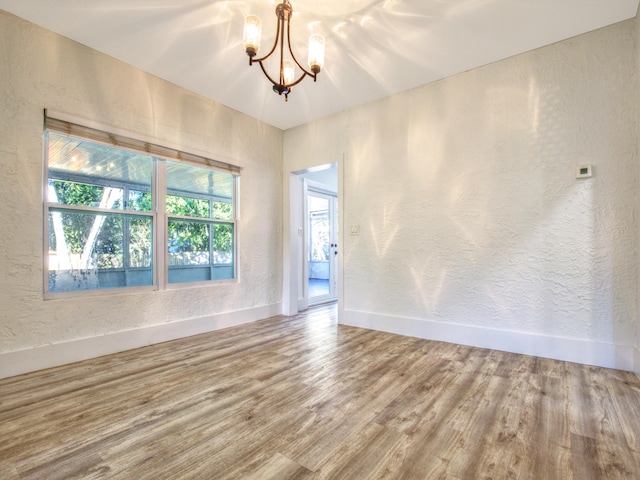 unfurnished room with hardwood / wood-style floors and an inviting chandelier