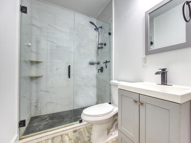 bathroom with toilet, a marble finish shower, wood finished floors, and vanity