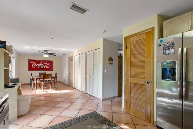 kitchen with light tile patterned flooring, ceiling fan, stainless steel fridge with ice dispenser, and white cabinetry