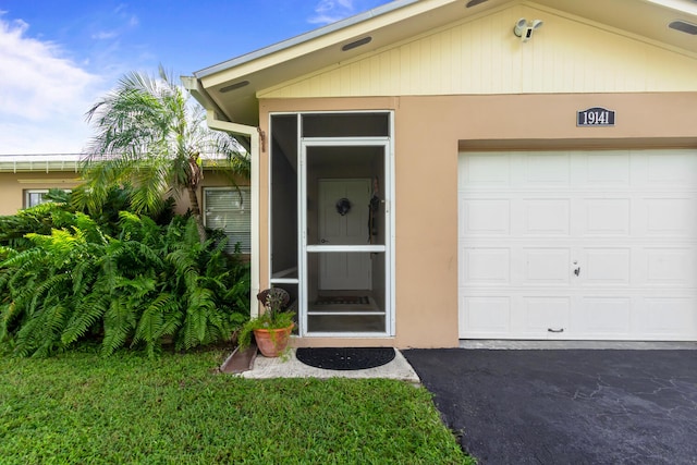 view of exterior entry featuring a yard and a garage