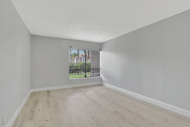 spare room featuring light wood-type flooring and a textured ceiling