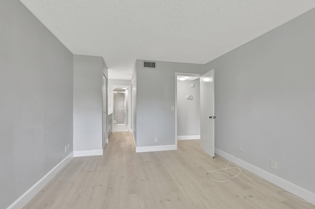 spare room with a textured ceiling and light hardwood / wood-style flooring