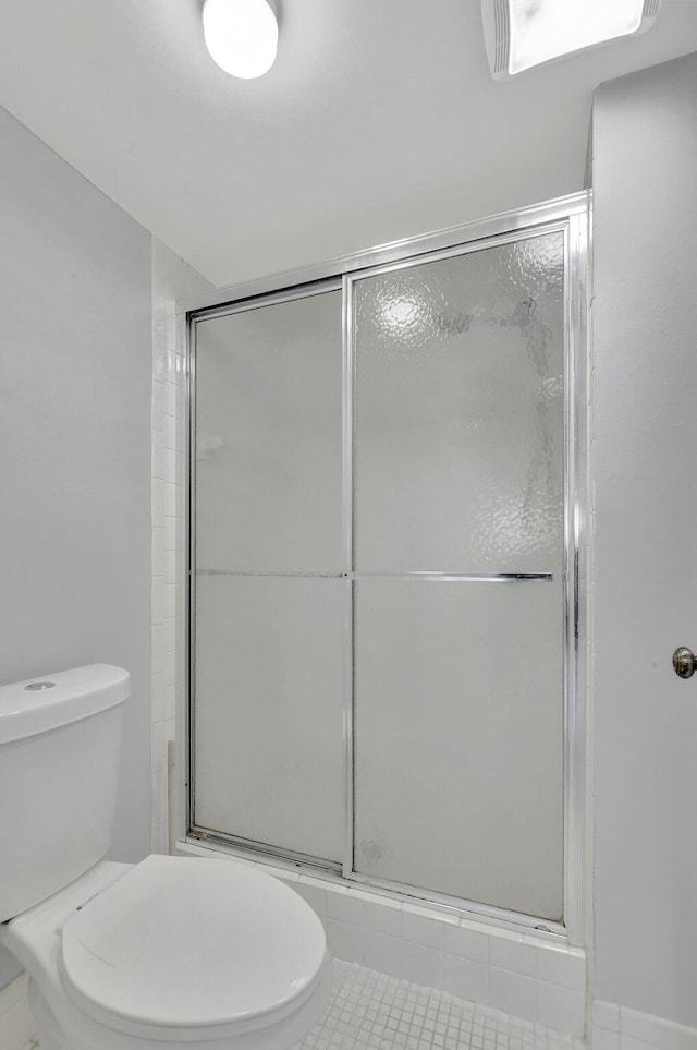 bathroom with tile patterned flooring, toilet, and a shower with shower door