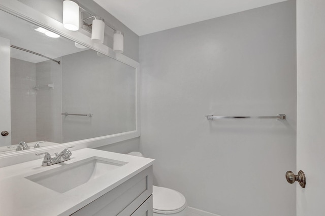 bathroom with a tile shower, vanity, and toilet