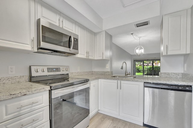 kitchen with light stone counters, sink, light hardwood / wood-style flooring, white cabinetry, and appliances with stainless steel finishes